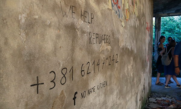 En una pared es llegeix el telèfon de NNK i el missatge que ajuden a refugiats