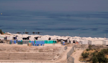 Vista des de lluny del camp de refugiats de Lesbos, amb tanques i tendes blanques davant del mar.