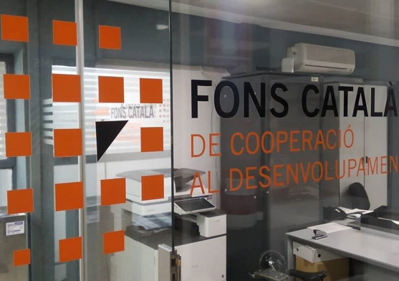 Logo del Fons Català en un vidre on es veu un espai d'oficina