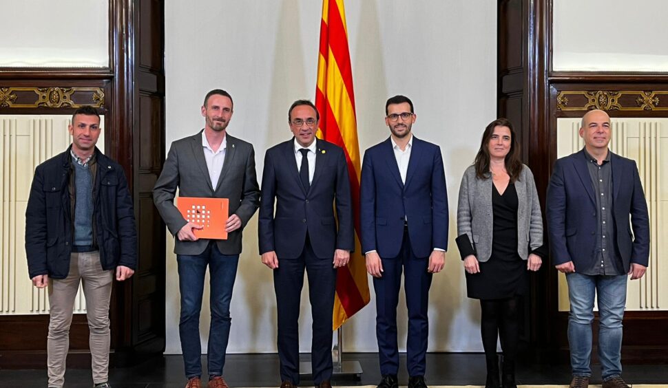 Els membres de la junta permanent i el director del Fons Català amb Josep Rull al centre posant per una fotografia amb la bandera de catalunya al darrere